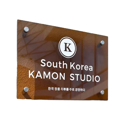 Glass sign with 'South Korea KAMON STUDIO' and a logo on a white background