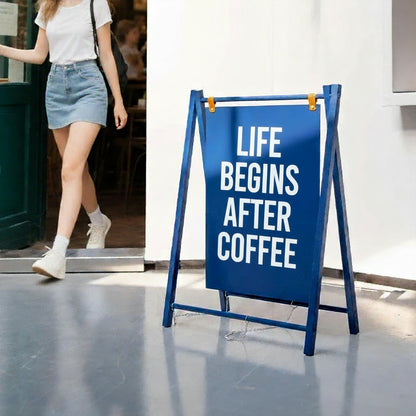 Blue a-frame sign with 'Life begins after coffee' message outside a restaurant, person walking by.