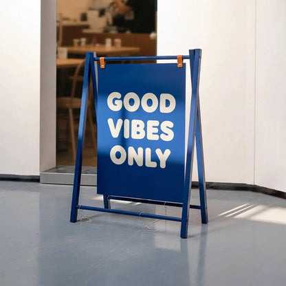 Blue a-frame sign with 'Good Vibes Only' message in a restaurant setting