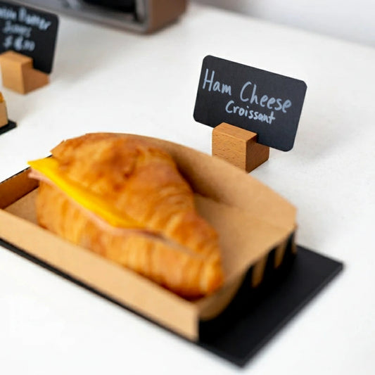 Croissant with cheese on a black stand with a price tag in the background