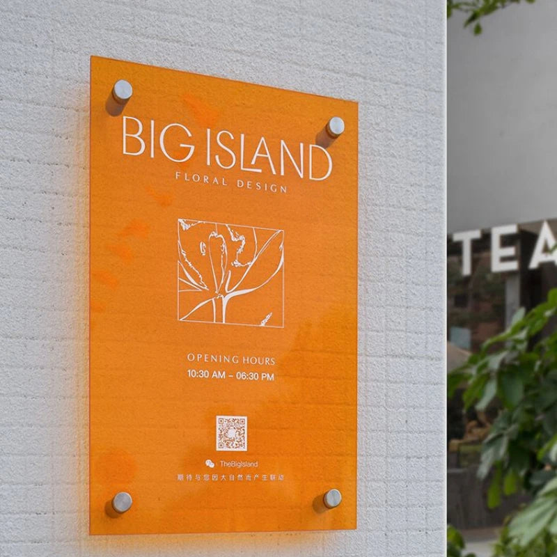 Orange signboard with 'BIG ISLAND FLORAL DESIGN' on a light gray wall.