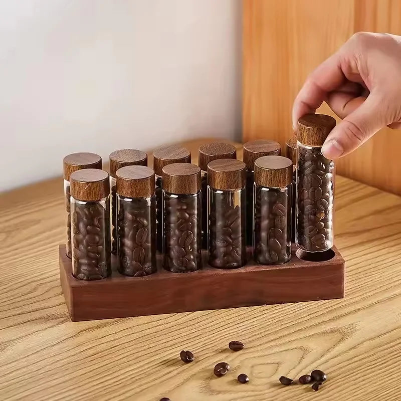 Wooden holder with glass vials containing coffee beans on a wooden surface.