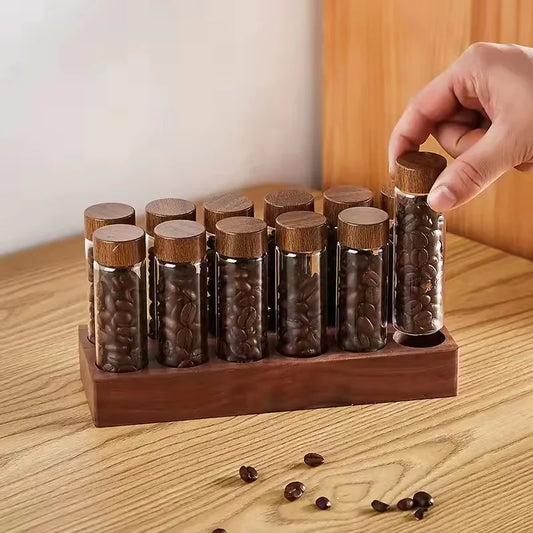 Wooden holder with glass vials containing coffee beans on a wooden surface.