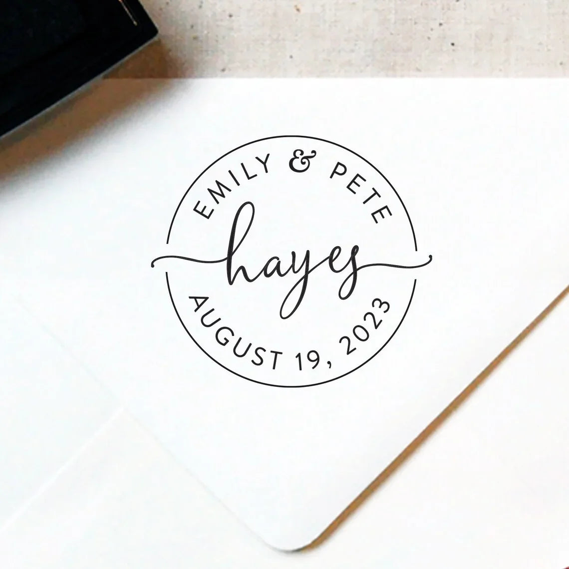 Personalized stamp with names 'Emily & Pete' and date 'August 19, 2023' on a white surface.